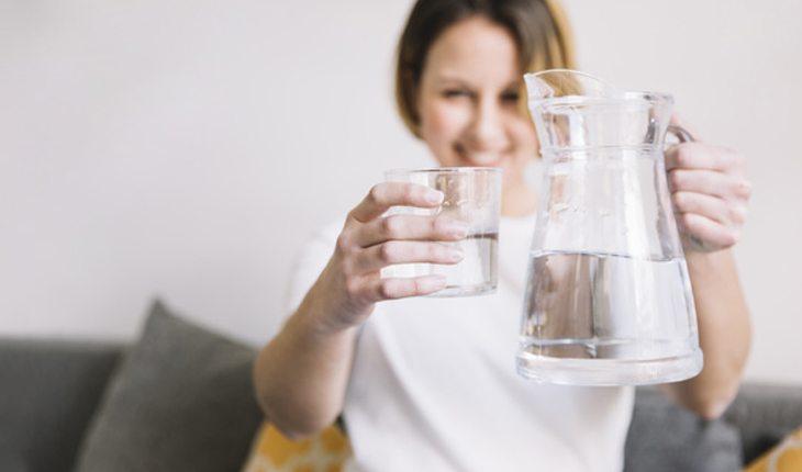 mulher segurando uma jarra e um copo com água