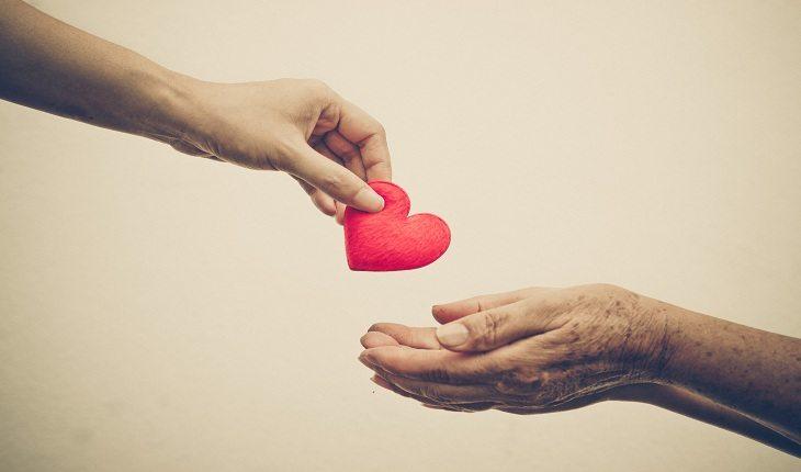 foto de uma mão depositando um coração de papel nas mãos de outra