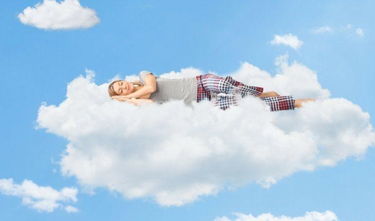 Mulher de pijama dormindo em cima de nuvem