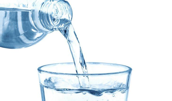 Garrafa de água transparente despejando líquido em copo