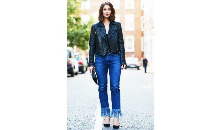 Mulher com jaqueta, calça jeans desfiada.