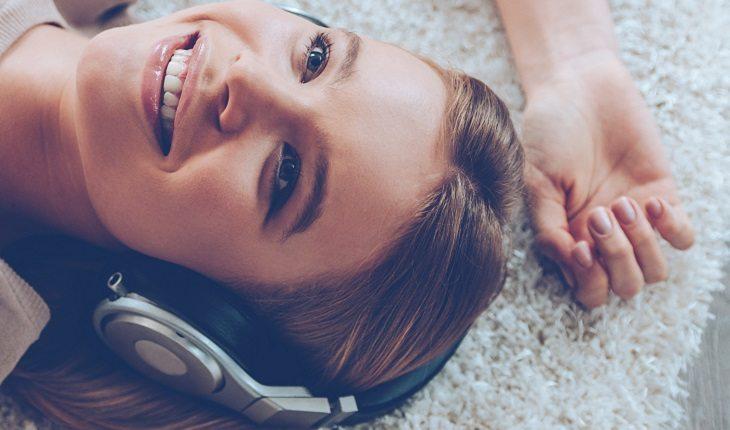 mulher ouvindo música deitada no chão sorrindo