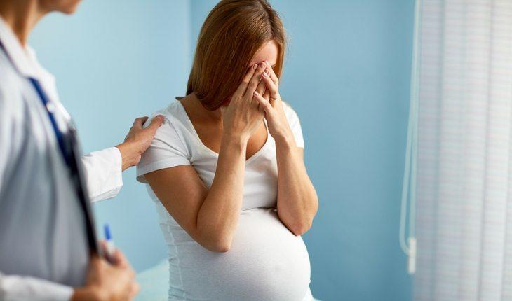 Mulher grávida sentada sendo atendida por médica