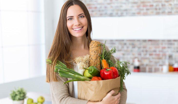 mulher carregando saco de compras com legumes