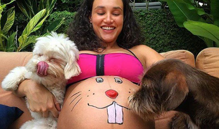 Débora Nascimento grávida com coelho desenhado na barriga e abraçando dois cachorros