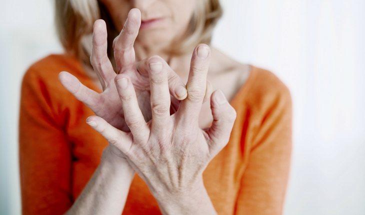 Mulher idosa olhando para as mãos e tocando os dedos
