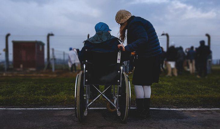 mulher ajudando pessoa em cadeira de rodas