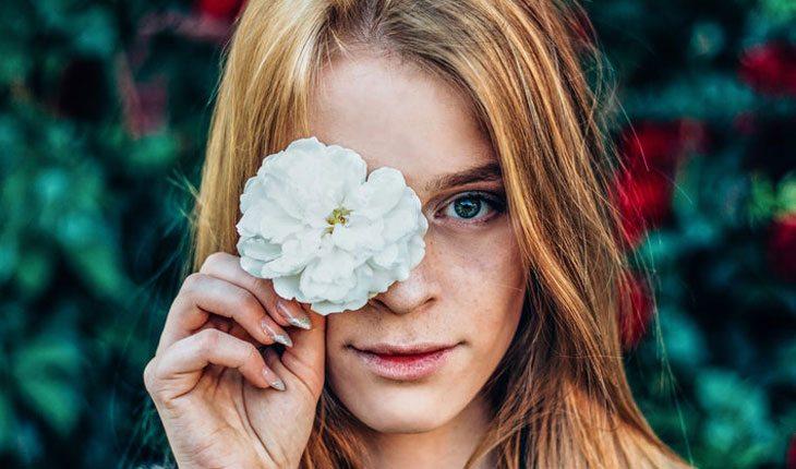 menina segurando flor na frente do rosto