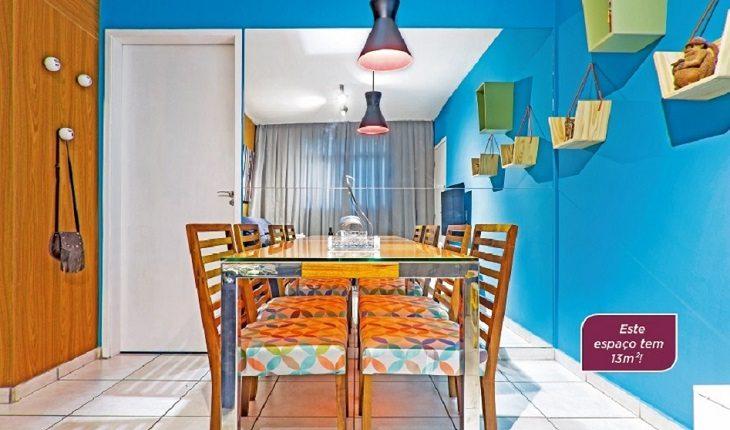 Mesa de jantar ao centro do cômodo com paredes coloridas em azuis