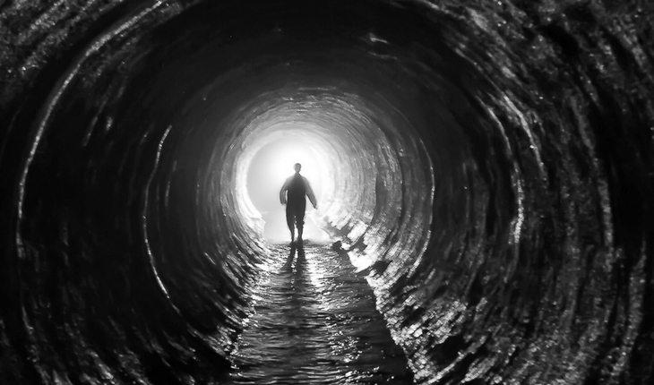 Homem caminhando por túnel escuro
