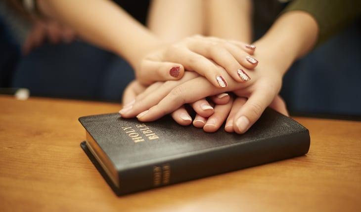mulheres com a mão em uma bíblia