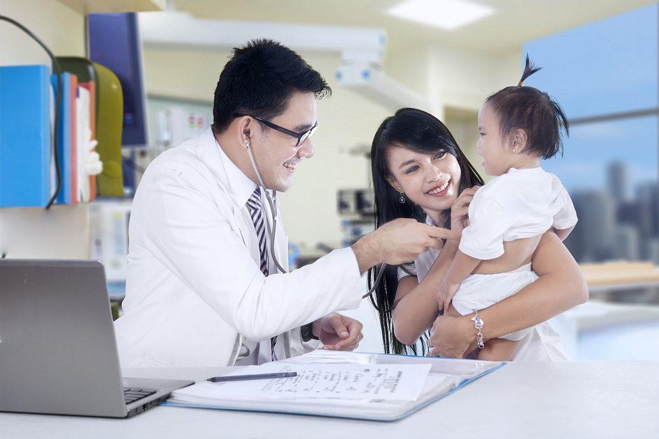 Médico japonês examinando criança. O bebê está chorando no colo da mãe.
