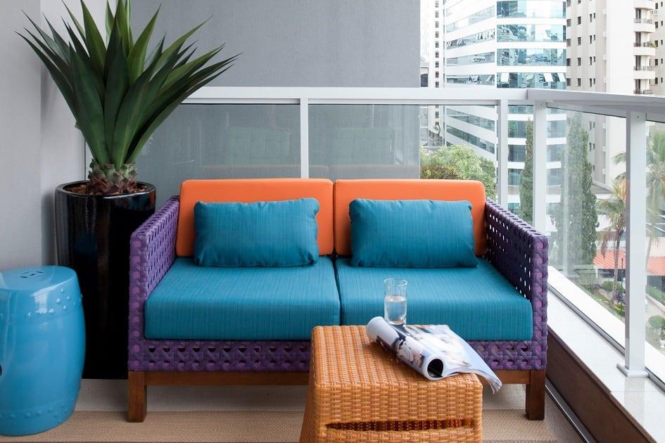 Varanda de um apartamento com sofás e poltronas coloridas