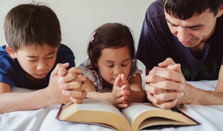 Família rezando em cima de Bíblia