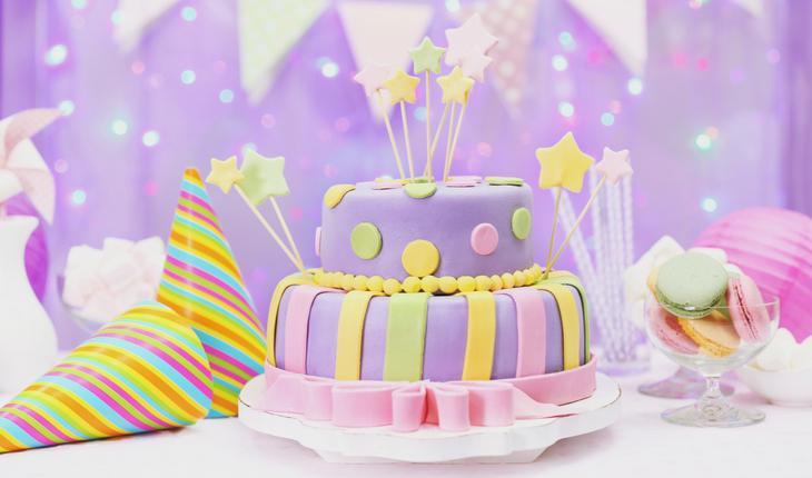 Decoração de festa de aniversário em violeta com bolo confeitado e chapéu de aniversário
