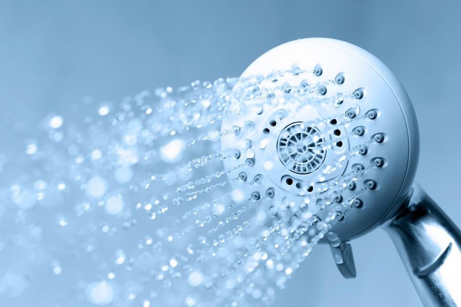 Um chuveiro aberto com água saindo para ilustrar o tema ressecamento de pele 