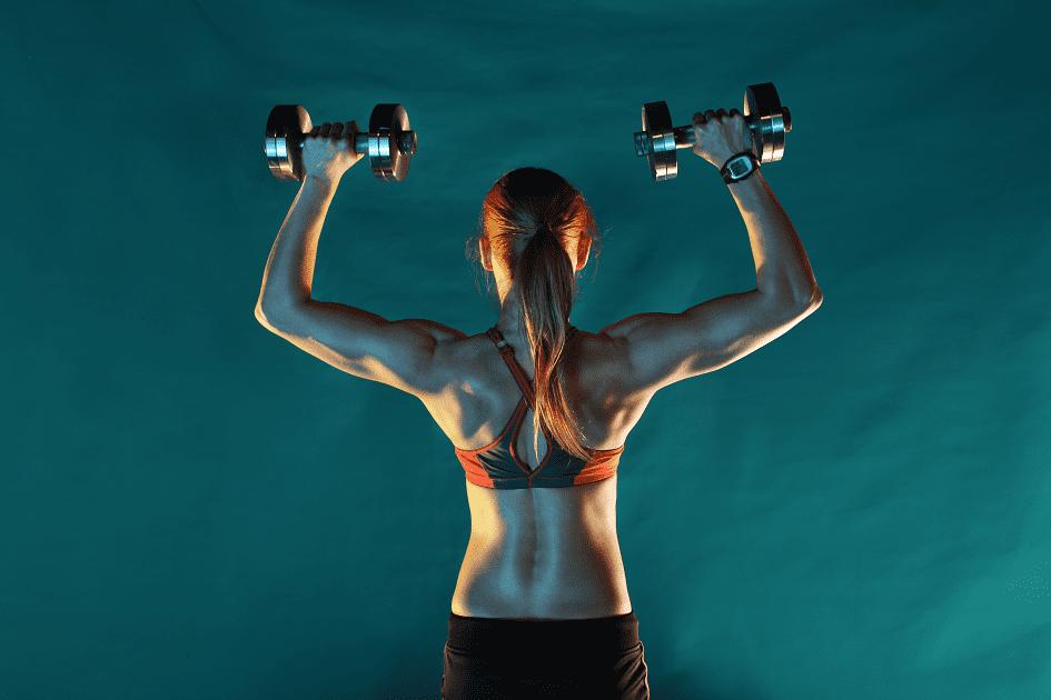 mulher de costas segurando dois halteres para ilustrar o tema exercícios para costas e ombros 