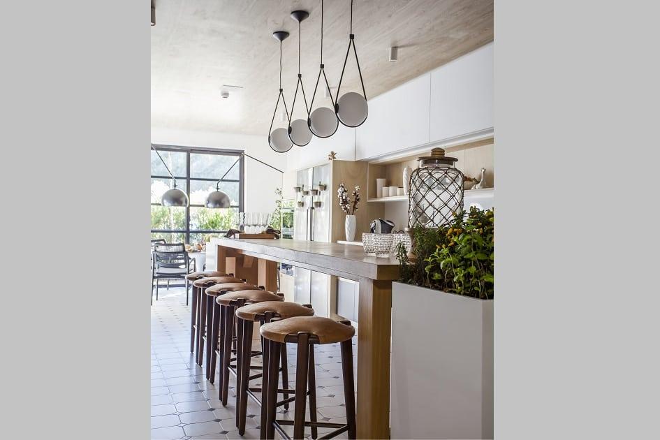 Foto de cozinha: balcão branco com bancos de madeira e pendentes de luz redondos e modernos
