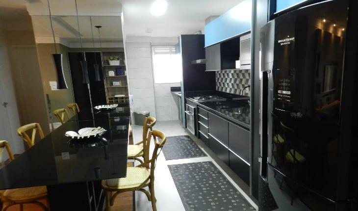Foto em perspectiva de uma cozinha com armários escuros em tom de preto e azul e revestimento geométrico branco e cinza