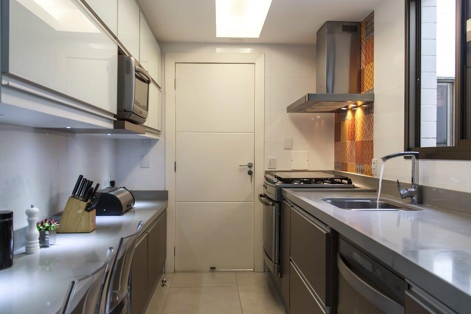 Cozinha com detalhes em ladrilhos alaranjados, armários em madeira, equipamentos em inox e cores claras
