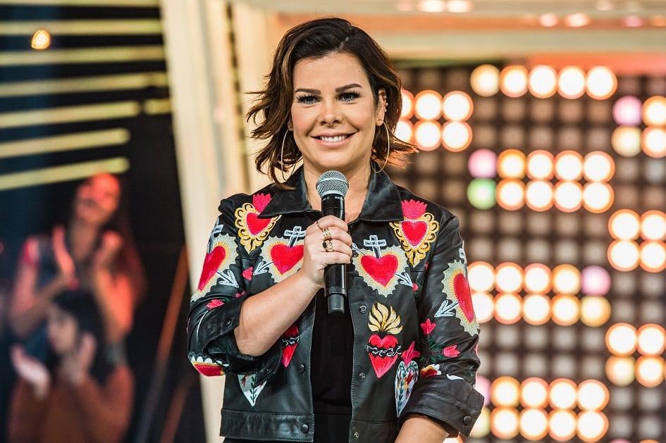 Foto da apresentador Fernanda Souza de cabelo castanho escuro com canhel repicado. Ela veste uma jaqueta de couro com alguns corações vermelhos estampados 
