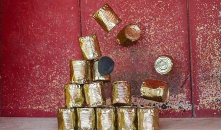 objeto acertando pilha de latas pintadas de dourado