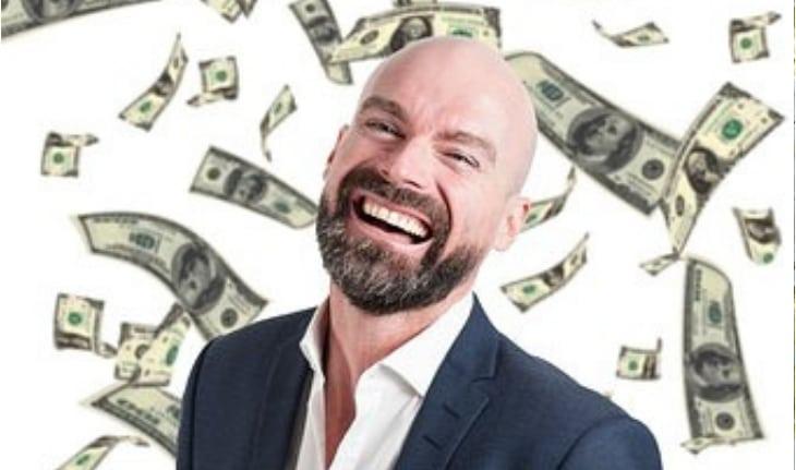 homem branco careca rindo com notas de dinheiro caindo atras