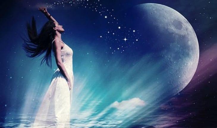 mulher de vestido branco olhando para cima com lua ao fundo e luzes no chão