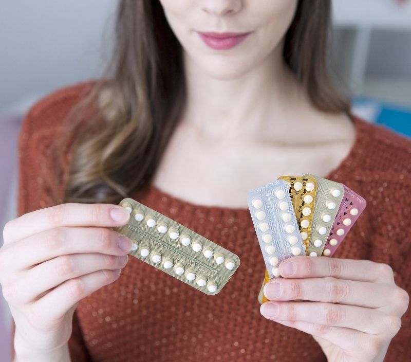 Mulher segurando várias cartelas de anticoncepcional